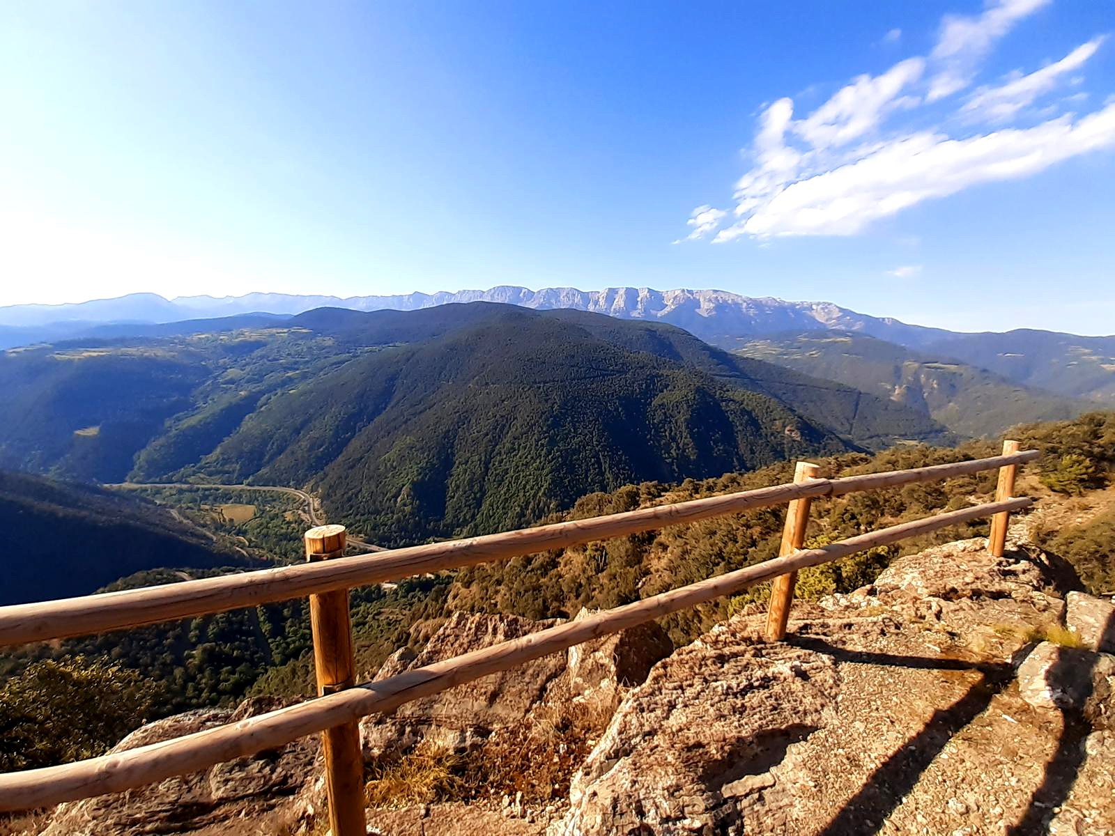 Foto d'un mirador on es veu una valla de fusta en primera línia i muntanyes de fons.